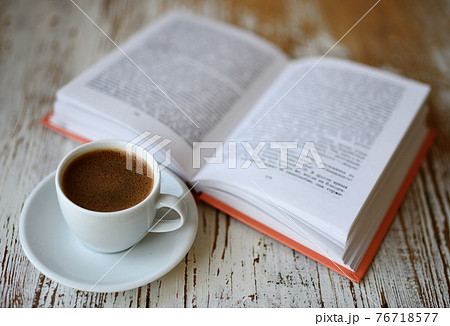 Cup of coffee and a book on table 76718577
