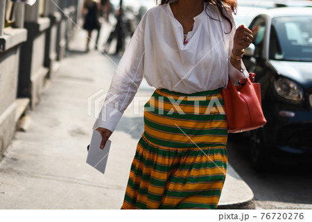 Detail of a fashionable outfit woman wearing white shirt, yellow and green skirt and red handbag Detail of a fashionable outfit woman wearing white shirt, yellow and green skirt and red handbag 76720276