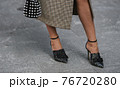 Detail of a fashionable outfit woman wearing black shoes and plaid coat 76720280