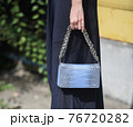 Detail of a fashionable outfit woman wearing blue dress and an aquamarine snake purse 76720282