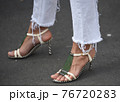 Detail of a fashionable outfit woman wearing white pants and white sandals with metal details 76720283