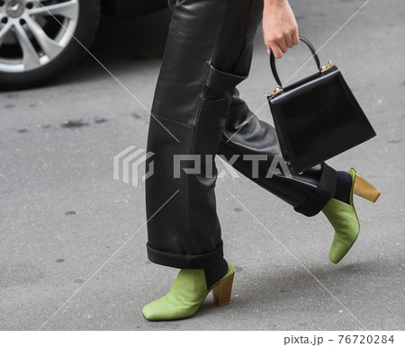 Detail of a fashionable outfit woman wearing green shoes, black handbag and black leather pants Detail of a fashionable outfit woman wearing green shoes, black handbag and black leather pants 76720284