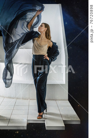 Woman in a blue dress posing with a fluttering fabric 76720898