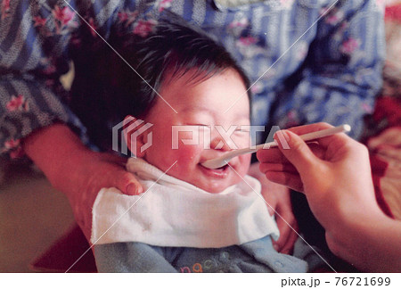 昔のフィルム写真　ごはんを食べて笑っている幼児 76721699