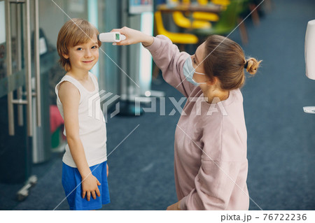 Child temperature measurement woman by laser thermometer at kindergarten. 76722236