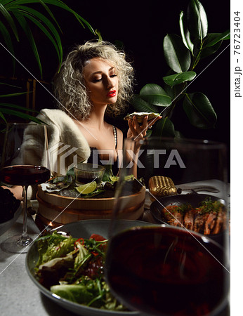 Bohemian glamour woman in black dress has a dinner 76723404