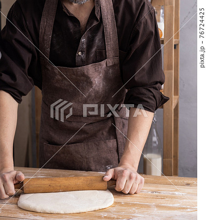Baker man kneading or making dough or bread cooking. Bakery concept and wooden table 76724425