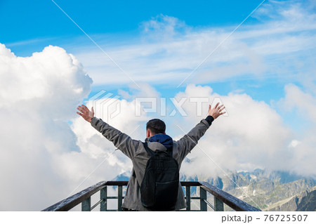 Tourist standing on the observation deck and enjoying of amazing view of mountains peak and clouds 76725507