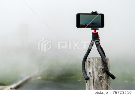 Smartphone on the tripod taking photos. Capturing image or time lapse of moving clouds in the mountains. Device for blogging Smartphone on the tripod taking photos. Capturing image or time lapse of moving clouds in the mountains. Device for blogging 76725510