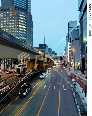 夕方の東京新宿の道路と車と雑居ビル 76725669
