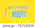 Words GOODBYE COVID 19 from wooden letters, syringe and facemask. Vaccination and the end of epidemic concept. 76726036