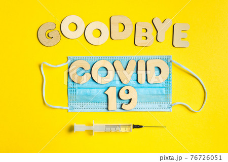 Words GOODBYE COVID 19 from wooden letters, syringe and facemask. Vaccination and the end of epidemic concept. 76726051