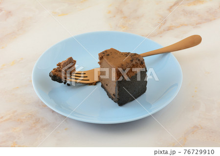 Slice of Belgian chocolate cheesecake with missing bite and copper fork on blue dessert plate Slice of Belgian chocolate cheesecake with missing bite and copper fork on blue dessert plate 76729910