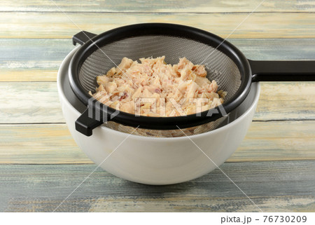 Rinsed canned albacore tuna draining in strainer into white bowl Rinsed canned albacore tuna draining in strainer into white bowl 76730209