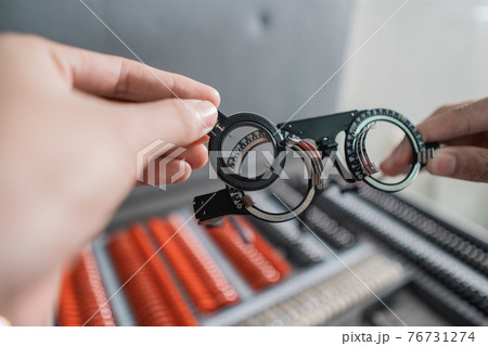 a doctor's hand is holding the experimental lens frame in a room a doctor's hand is holding the experimental lens frame in a room 76731274
