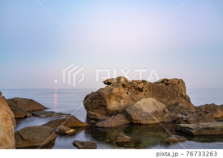 Twilght over the wild rocky beach coastline and the sea. Sea and rocks at night wide angle view. Twilght over the wild rocky beach coastline and the sea. Sea and rocks at night wide angle view. 76733263