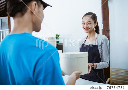 portrait courier smiling bring the package for young female shopkeeper portrait courier smiling bring the package for young female shopkeeper 76734781