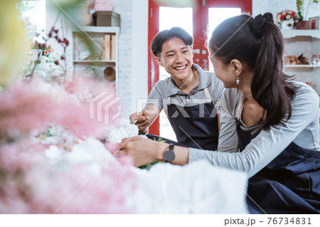 portrait young couple wearing apron smiling talking while working together portrait young couple wearing apron smiling talking while working together 76734831