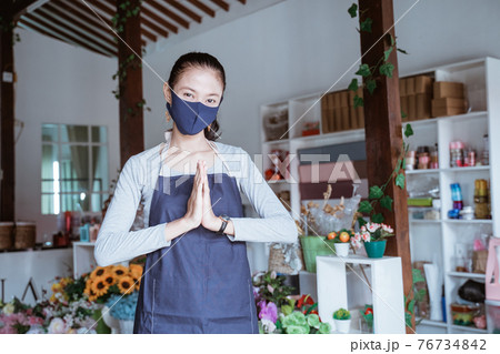 young woman manager wearing apron and face mask florist standing pose greeting young woman manager wearing apron and face mask florist standing pose greeting 76734842