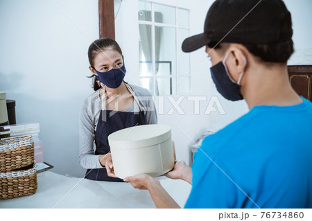 smiling young female shopkeeper receiving a package 76734860