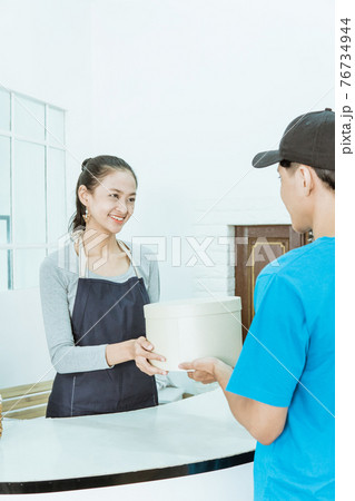 smiling young female shopkeeper receiving a package smiling young female shopkeeper receiving a package 76734944