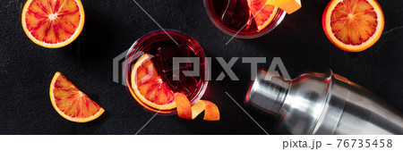 Negroni cocktails panorama with blood oranges on black Negroni cocktails panorama with blood oranges on black 76735458
