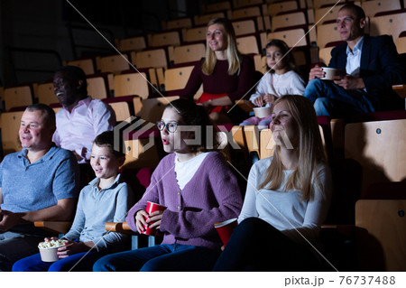 Spectators eating popcorn and watching movie at the cinema Spectators eating popcorn and watching movie at the cinema 76737488