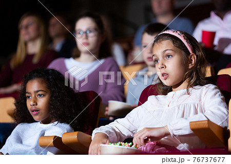 kids sitting at movie in auditorium in cinema 76737677
