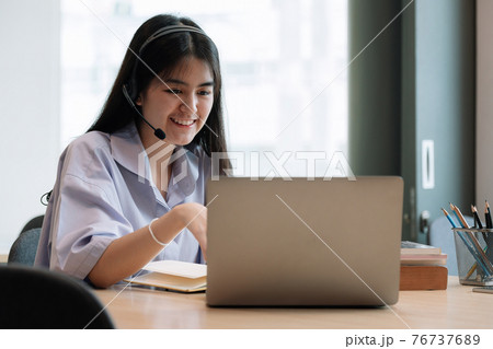 Asian young female student sitting while using headphones and laptop computer when studying online Asian young female student sitting while using headphones and laptop computer when studying online 76737689