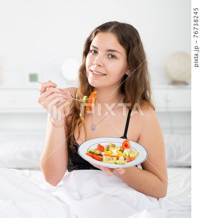 Young attractive smiling woman eating salad for breakfast 76738245