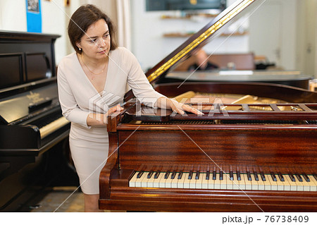 Beautiful girl chooses a piano in a music store Beautiful girl chooses a piano in a music store 76738409