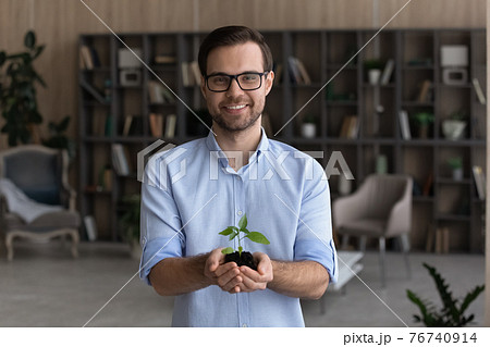 Portrait of smiling businessman hold seedling in hands Portrait of smiling businessman hold seedling in hands 76740914