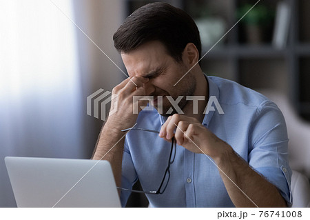 Exhausted man suffer from headache working on laptop Exhausted man suffer from headache working on laptop 76741008