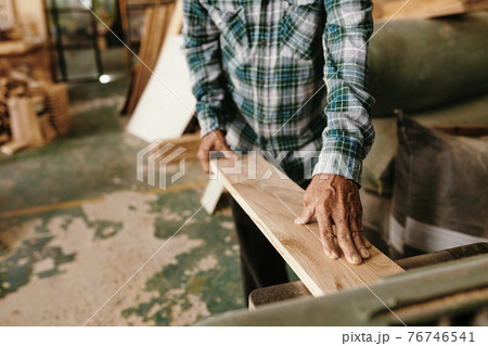 Carpenter putting board in thickness planer Carpenter putting board in thickness planer 76746541