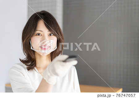 感染拡大防止のためにお客様の体温を計測するスタッフ 感染拡大防止のためにお客様の体温を計測するスタッフ 76747057