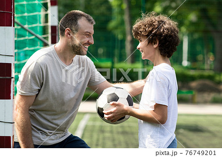 Sportive adult dad playing soccer with his son 76749201
