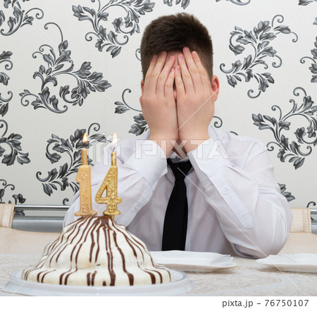 teen boy at table with cake for his fourteenth birthday teen boy at table with cake for his fourteenth birthday 76750107
