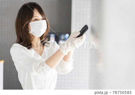 感染拡大防止のためにお客様の体温を計測するスタッフ 76750583