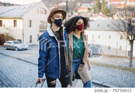 Young couple tourists with luggage walking on streets in old town, coronavirus concept. Young couple tourists with luggage walking on streets in old town, coronavirus concept. 76750615