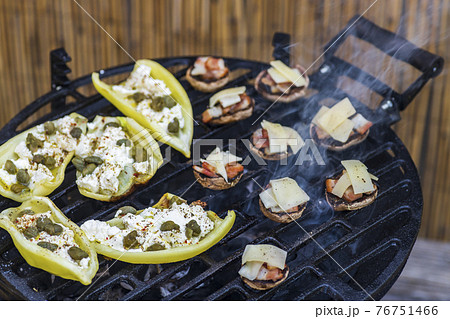 grilled peppers with feta cheese and capers and mushrooms with bacon baked with Emmental cheese 76751466