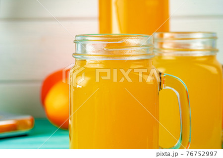 Glass with orange juice on green wooden table Glass with orange juice on green wooden table 76752997