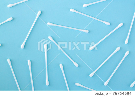 Pattern of white plastic cotton swabs or sticks top view on blue background Pattern of white plastic cotton swabs or sticks top view on blue background 76754694