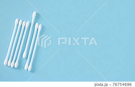 Flay lay of white plastic cotton sticks or swabs top view on blue background Flay lay of white plastic cotton sticks or swabs top view on blue background 76754696