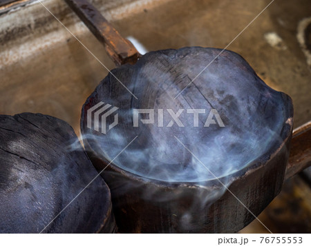 Steam rises from a wooden mold to form melted glass. Glass blowing studio 76755553
