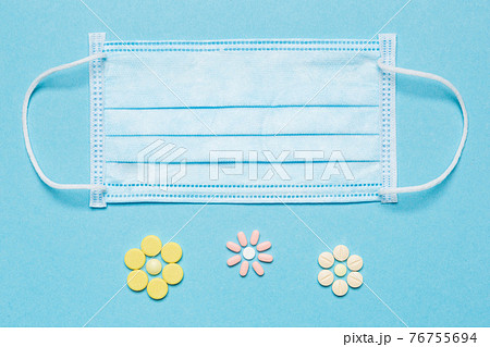 medical mask on a blue background and tablets are made in the form of flowers, concept allergy 76755694