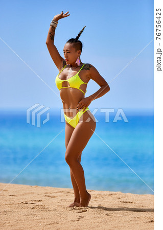Sexy asian gir in yellow swimsuitl dancing at the tropical beach 76756425