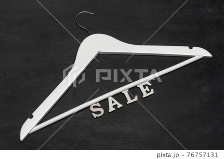 White hanger and SALE inscription on black background. Discounts. Seasonal sale. Special offer. Black friday. White hanger and SALE inscription on black background. Discounts. Seasonal sale. Special offer. Black friday. 76757131