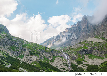 Mountain stream with view of rocky mountains at good weather.  76758612