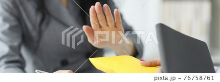 Woman refuses yellow envelope from sponsor in office closeup Woman refuses yellow envelope from sponsor in office closeup 76758761