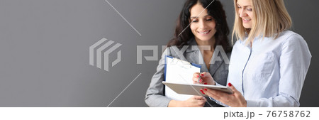 Businesswoman showing information to colleague on tablet and smiling 76758762